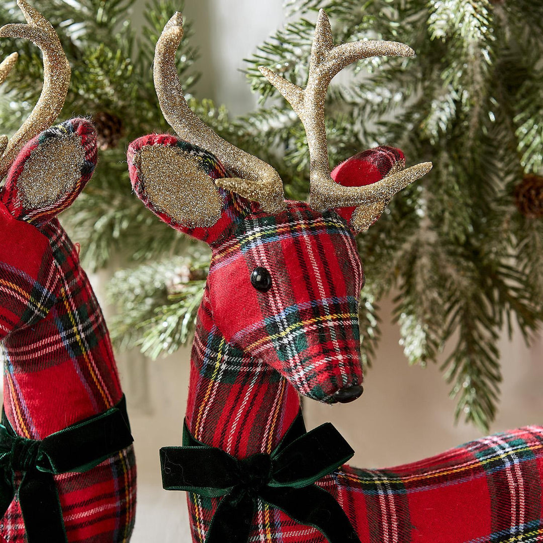 Two tartan reindeer figurines with gold antlers and green velvet ribbons.