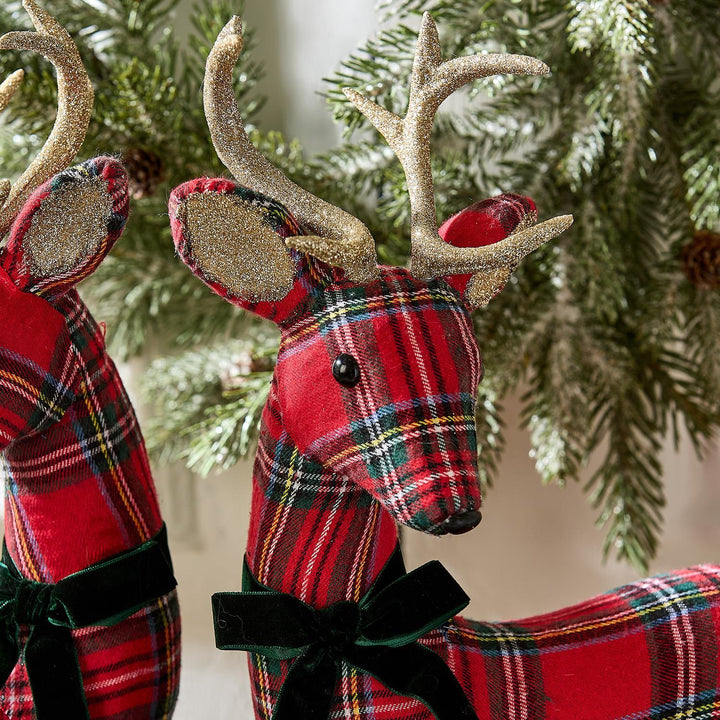 Two tartan reindeer figurines with gold antlers and green velvet ribbons.