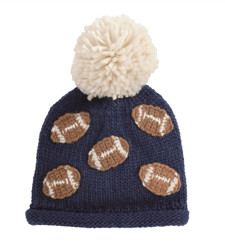 Chunky navy blue knit hat with white pom-pom and brown football appliqués around the crown; available in sizes S, M, and L.