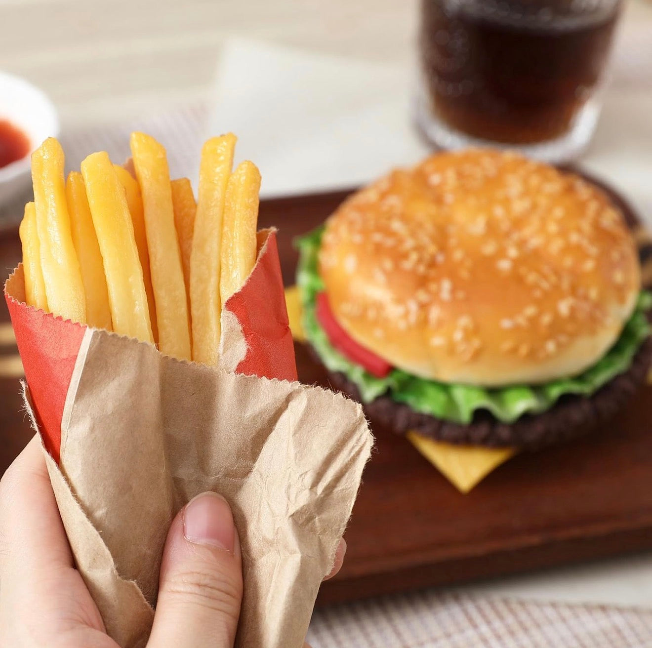 Paper-wrapped faux fries in hand. Available in small, medium, and large. Ideal for decorative display.