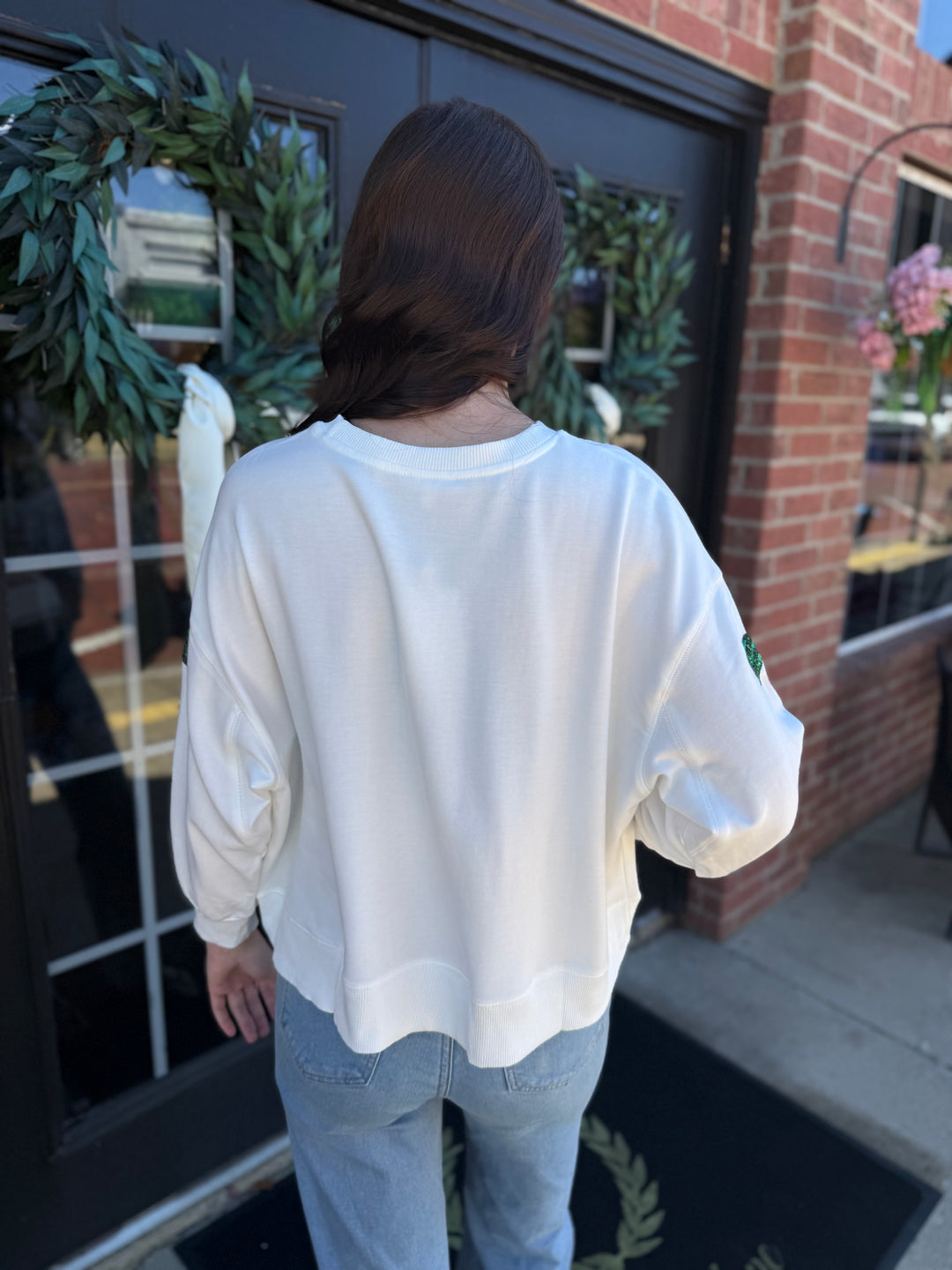 Millie Baubles &amp; Bows Sweatshirt: a white holiday crewneck with green sequined sleeve bows. Available in multiple sizes.