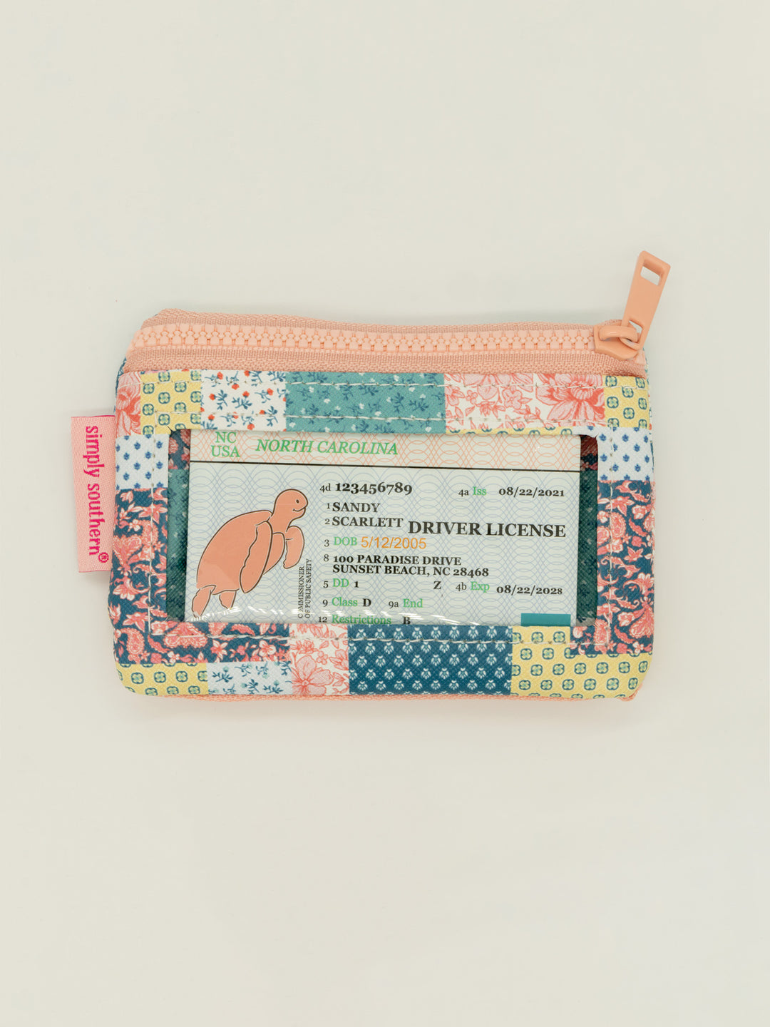 Compact, multicolored floral patchwork zip pouch with clear ID window, zippered pockets, peach keyring tag. Sizes: One size.