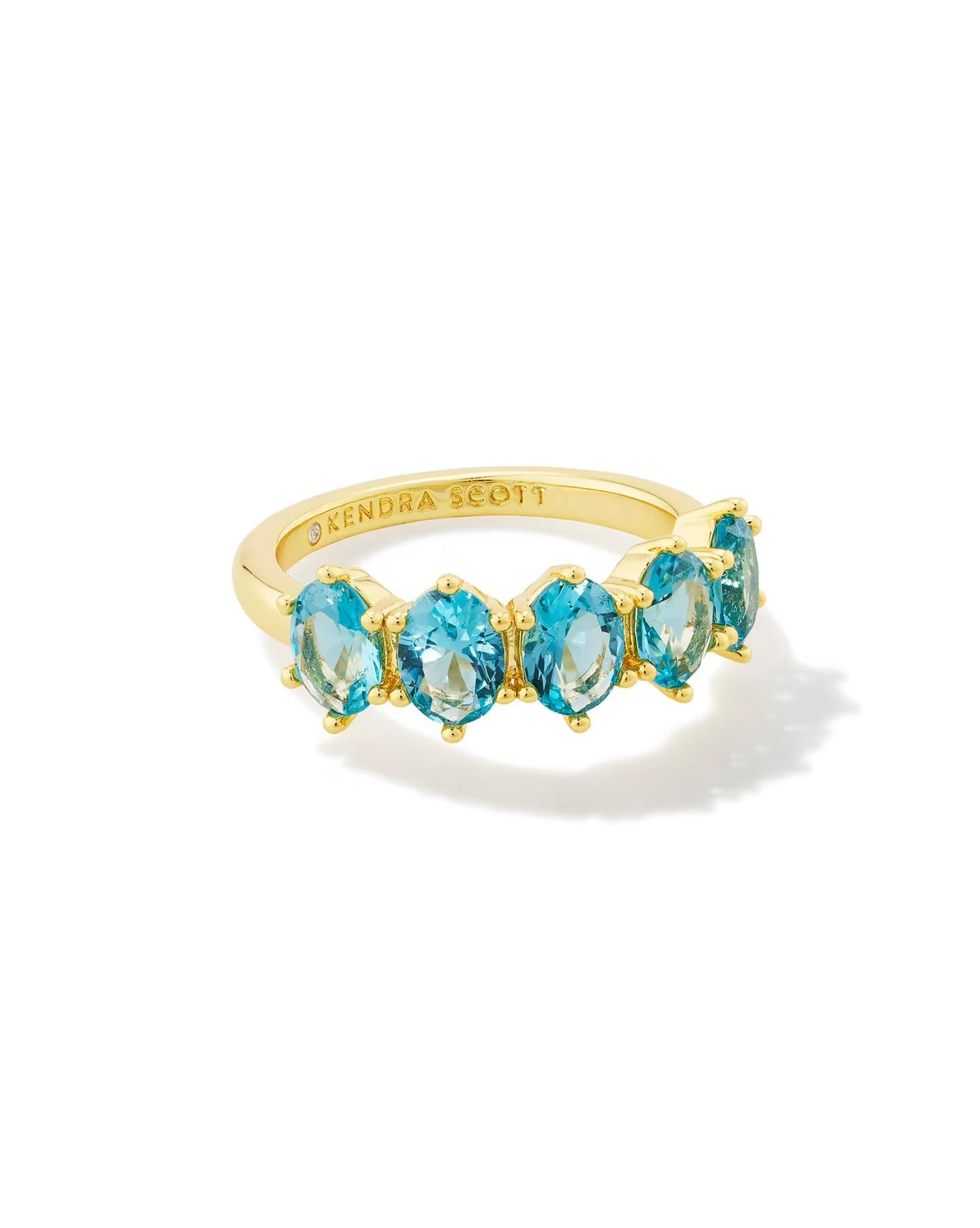 Gold band ring with five cobalt blue oval stones in a row, "Kendra Scott" engraved inside; available in sizes 5–9.