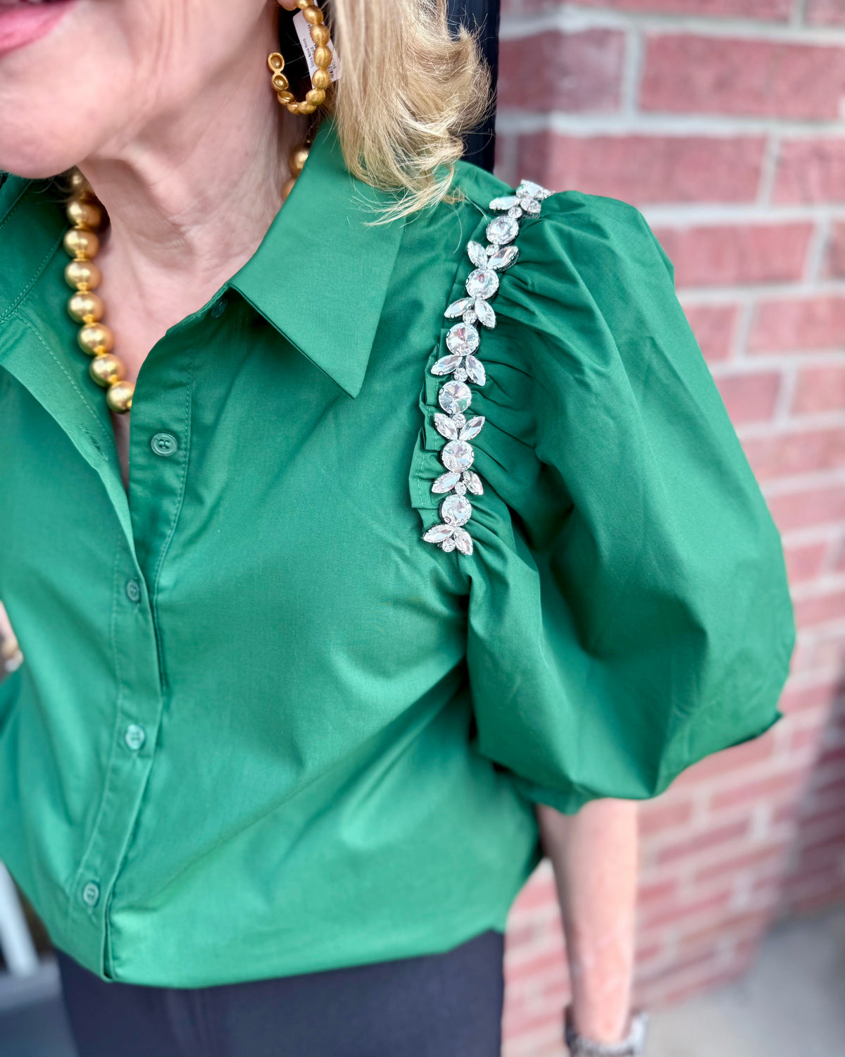 Hunter green Hadley Blouse with puff sleeves and rhinestone shoulder detail. Available in sizes XS–XL.