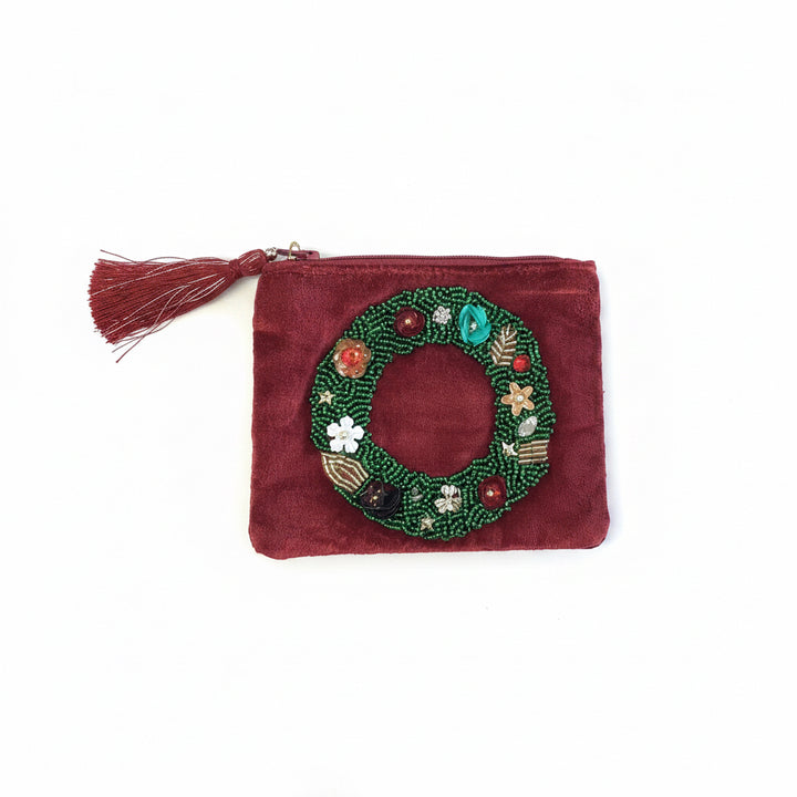 Deep red velvet holiday pouch with beaded wreath appliqué and tassel zipper pull.