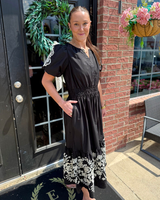 Tracey Aven Vines Black Dress with white floral embroidery and a smocked waist, available in sizes XS to XL.