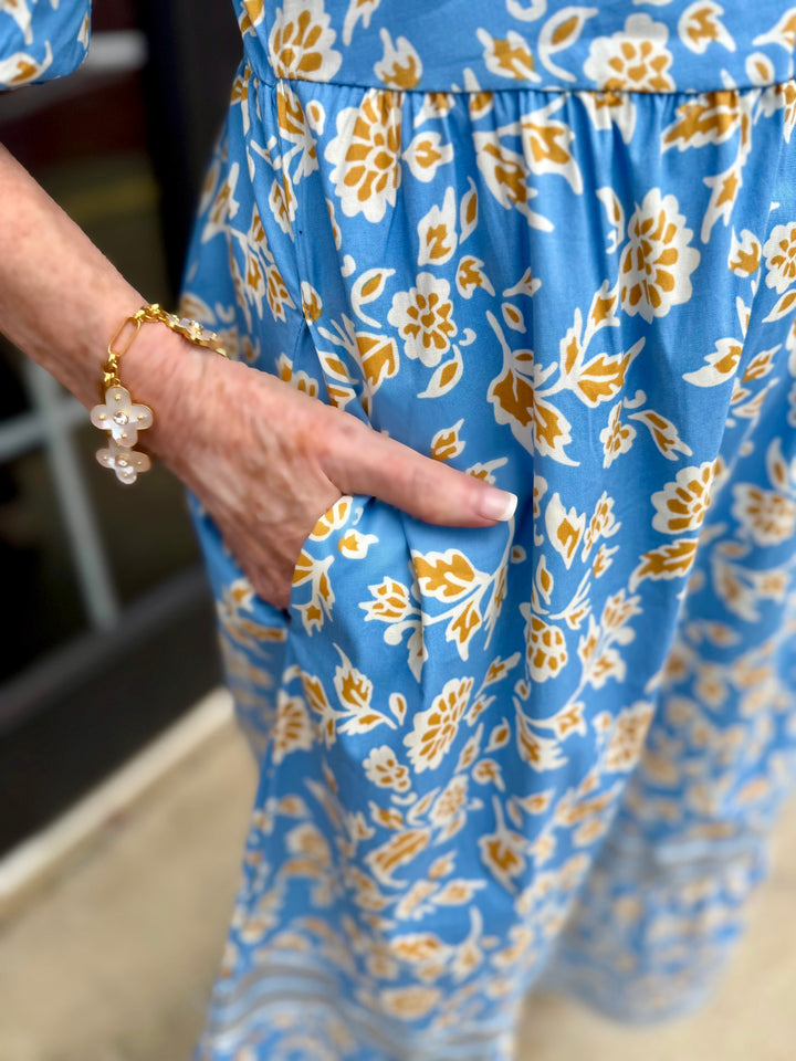 Riley Ivy Script Gold Dress in blue with white and yellow floral print, 3/4 sleeves, pockets. Sizes: XS-XL.