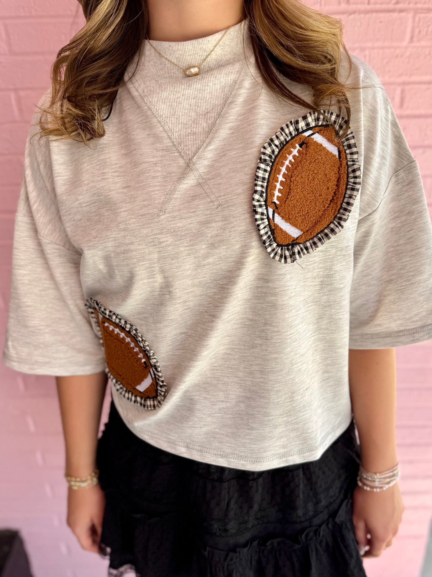 Gameday Gingham Football Patch Top: light gray, oversized cropped t-shirt with short sleeves and two brown football patches (chest and side). Available sizes: S, M, L, XL.