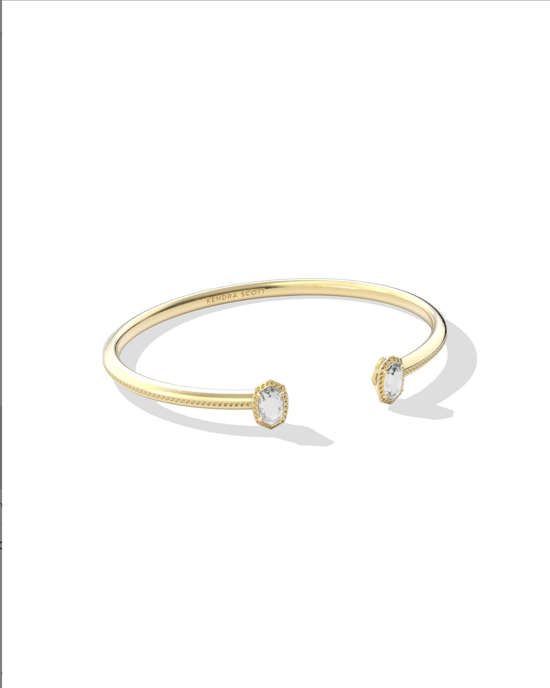 Slender gold cuff bracelet with open design and faceted white cubic zirconia stones at each end. Available in small, medium, and large sizes.