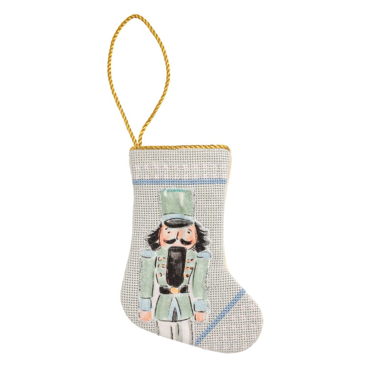 Needlepoint Nutcracker Mini Stocking ornament in a green uniform with a gold hanging cord.