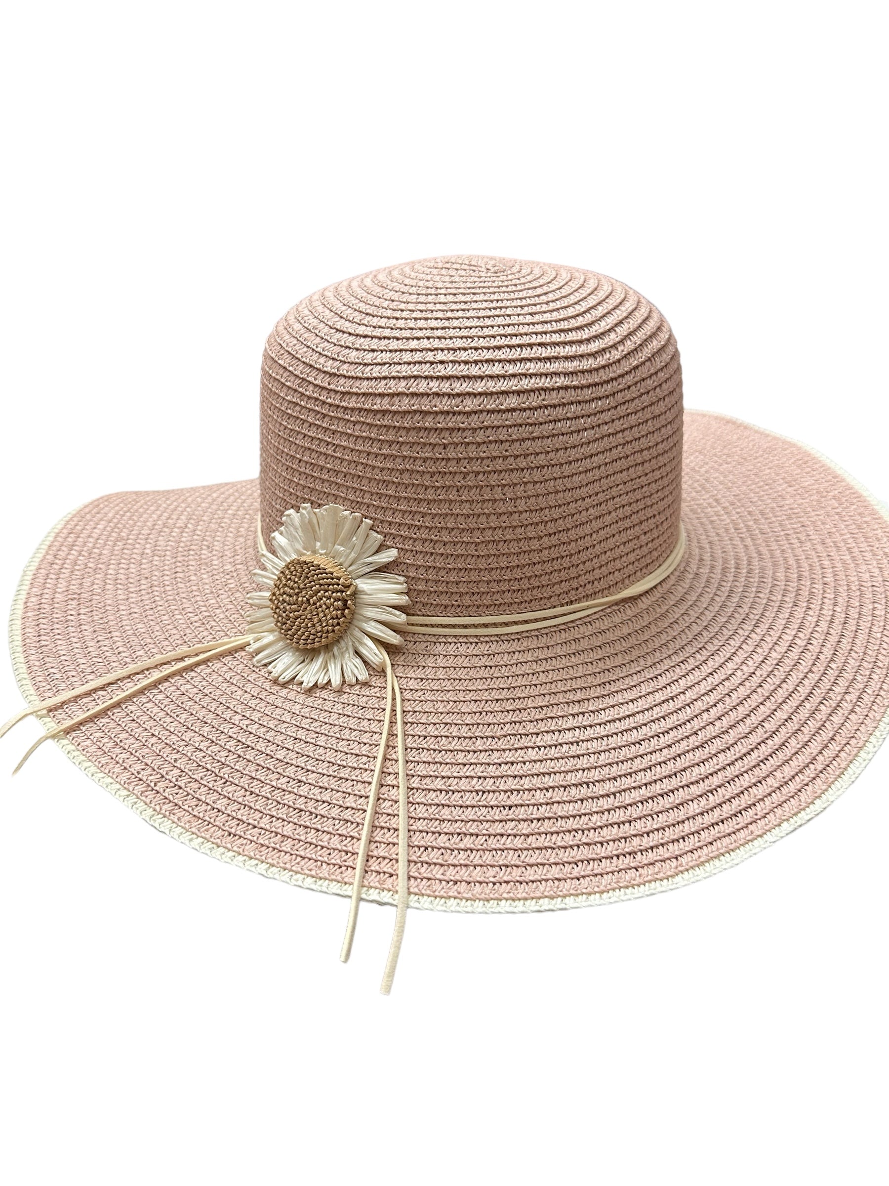 Fashionable sun hat with large brim in light pink, adorned with a white and yellow artificial daisy. Woven texture with decorative strings. Sizes: Medium, Large. Ideal for outdoor activities.