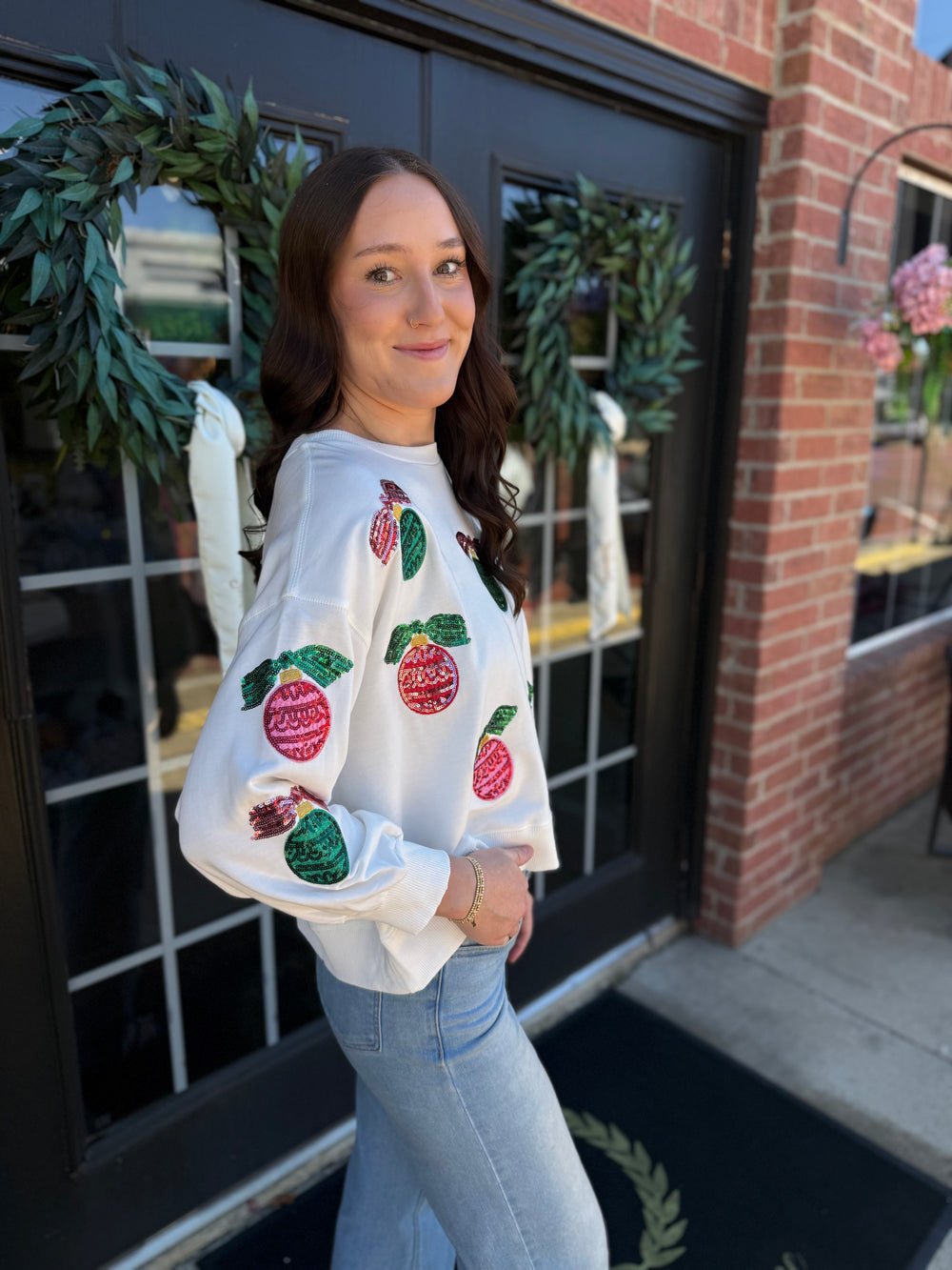 Millie Baubles & Bows white long-sleeve holiday sweatshirt with sequined ornament and bow motifs.