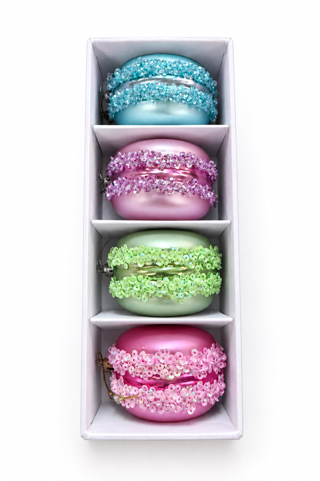 Set of four sequined macaron ornaments in light blue, purple, lime green, and pink, presented in a white gift box.