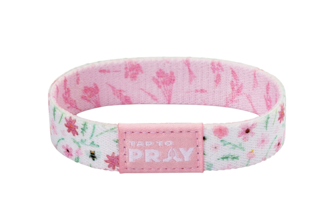 Tap To Pray™ Wristbands - Meadows: elastic fabric wristband with white and pink floral pattern and a pink “TAP TO PRAY” embossed tab. Available in various sizes.