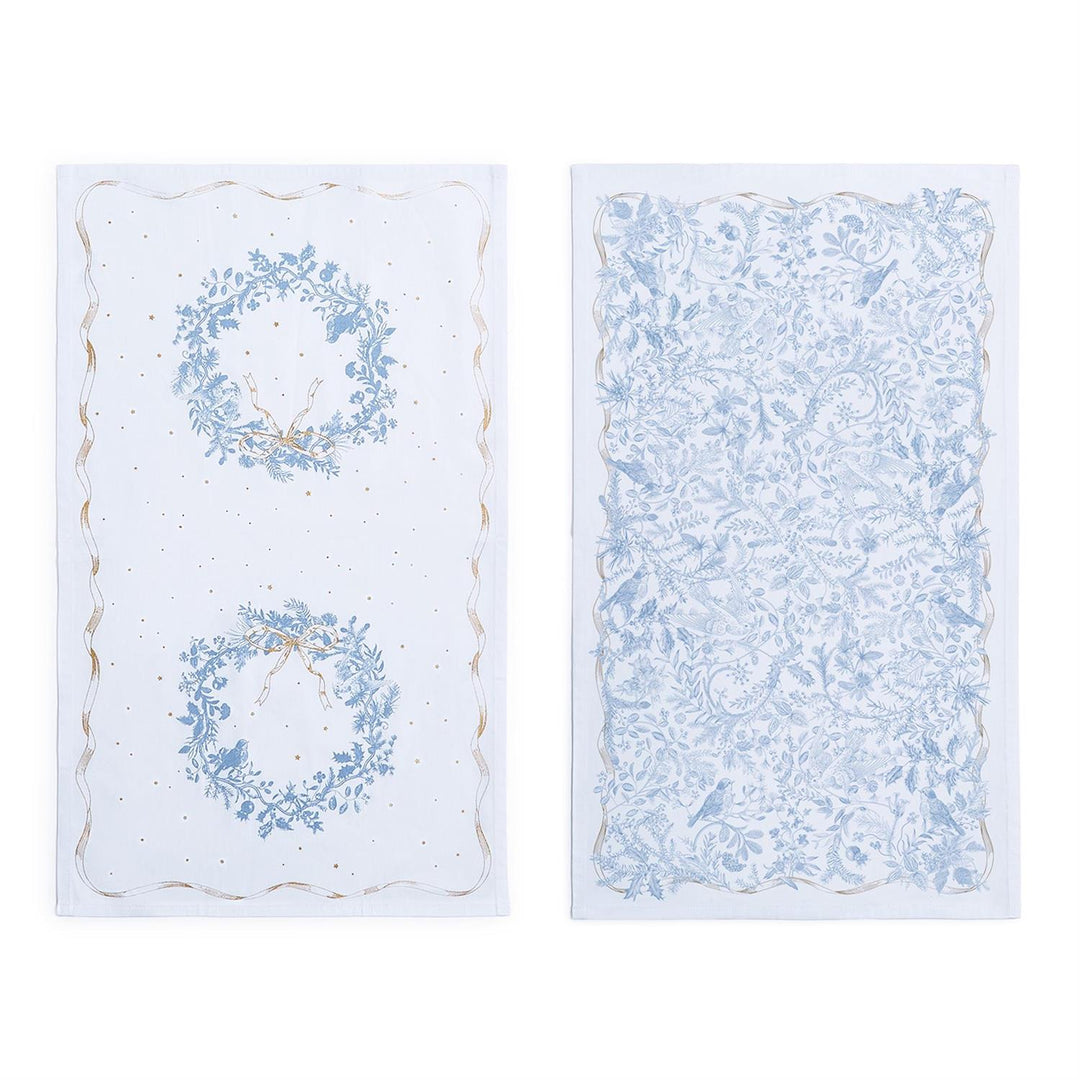Two white Gilded Cottage Dish Towels with blue botanical patterns, featuring wreath and bird prints with gold accents.