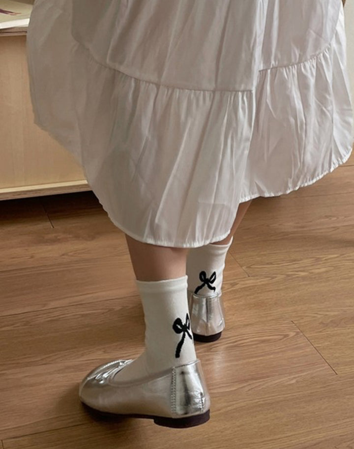 The product is a pair of Bow Mid-Calf Socks crafted with contrasting bow designs. These socks are available in multiple sizes to suit different foot dimensions.