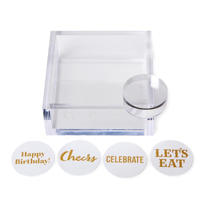 Acrylic cocktail napkin holder with paper weight, includes four round message cards in gold lettering: “Happy Birthday!”, “Cheers”, “CELEBRATE”, and “LET’S EAT”. Available in standard and large sizes.