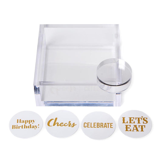 Acrylic cocktail napkin holder with paper weight, includes four round message cards in gold lettering: “Happy Birthday!”, “Cheers”, “CELEBRATE”, and “LET’S EAT”. Available in standard and large sizes.