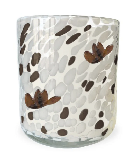 Into the Sunset" Soy Candle made from soy and vegetable wax in a clear glass tumbler, with brown and beige speckled patterns and two brown-orange flower shapes. Available in multiple sizes.