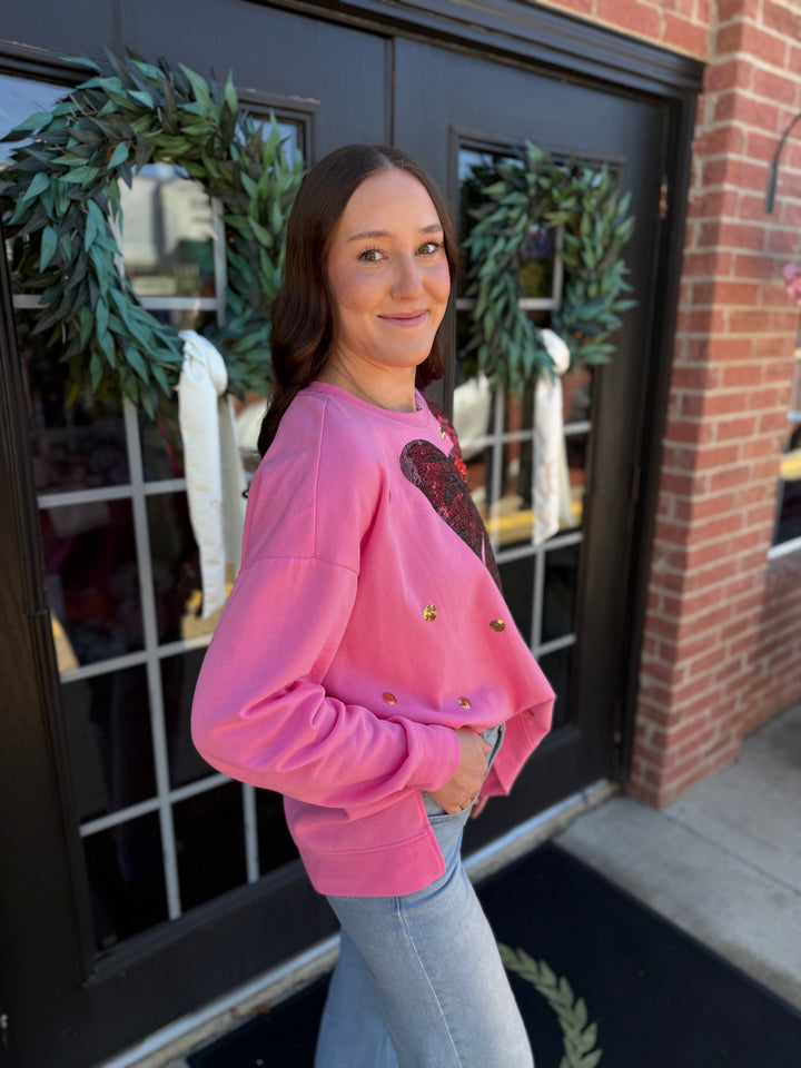 Relaxed pink Sequin Bow Sweatshirt with red chest bow and gold sequin embellishments. Available in all sizes.