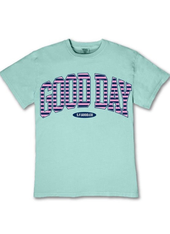 Light blue relaxed-fit tee, "GOOD DAY" in pink/blue/white 3D letters, "SF.GOOD.CO" below. Sizes: S–XL.