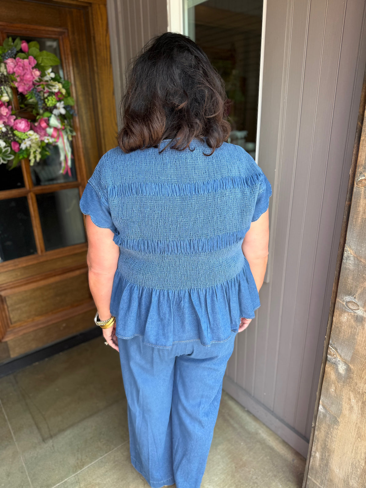 Blaire Chambray Smocked Peplum Top with scalloped ruffle sleeves, available in sizes XS–XL.