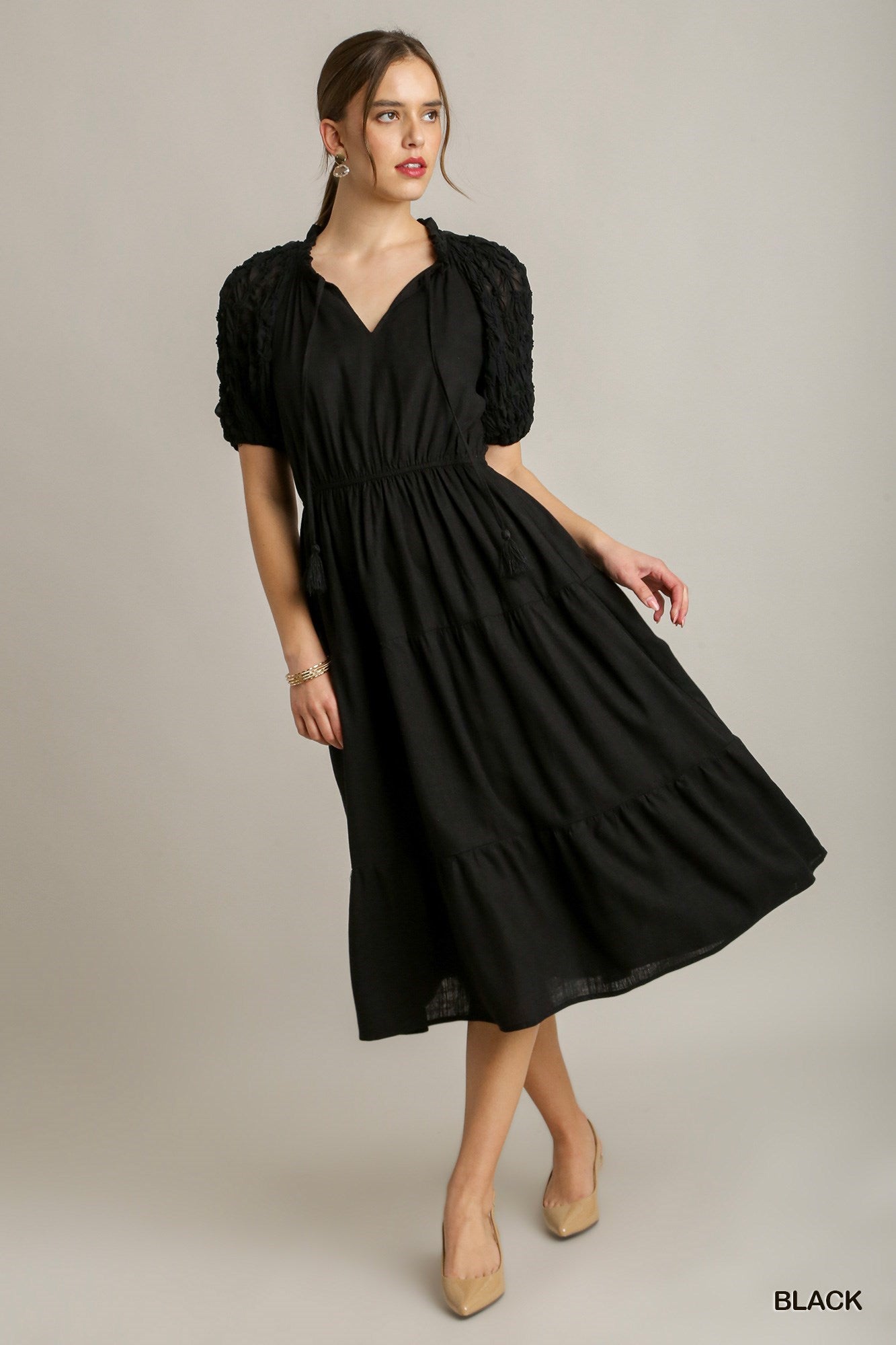 Black Ruffle Tiered Midi Dress with Front Tassel Drawstring and Textured Sleeves. The dress features a v-neckline and gathered waist. Available in sizes small, medium, large, and extra-large.