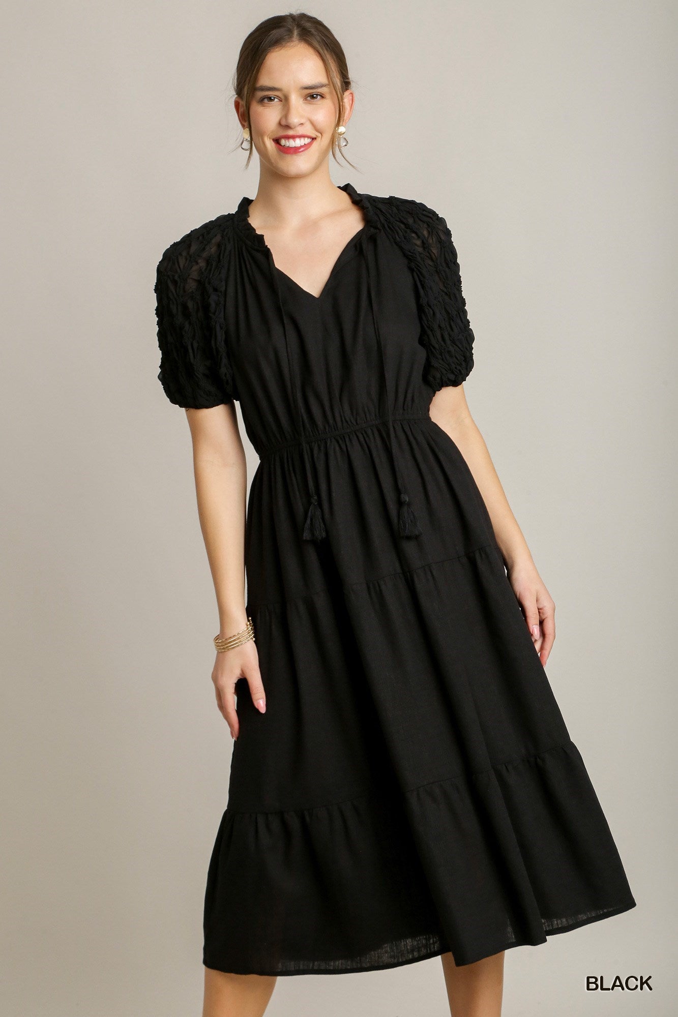 This is a Black Ruffle Tiered Midi Dress featuring Front Tassel Drawstring and Textured Sleeves. Available sizes for this product range from small to large.