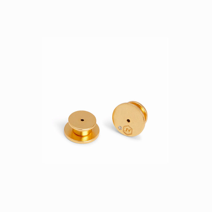 Two 24K gold-plated Honey Stud Iridescent Tourmaline Pink earring backs with engraved hexagon logo and embedded gemstone.