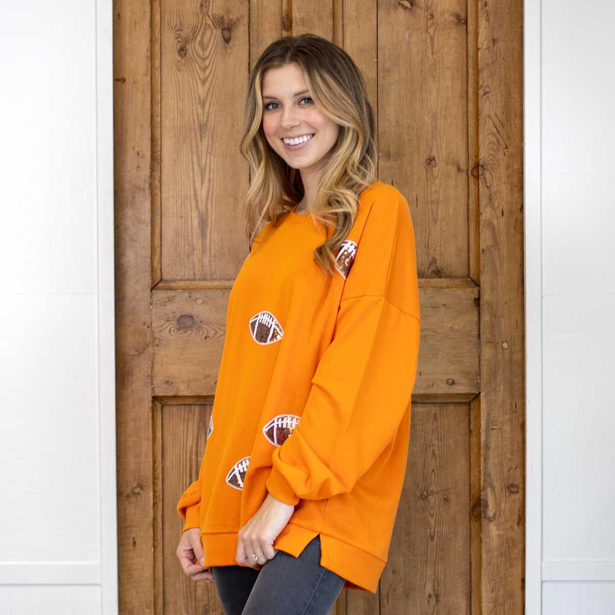 Football Queen Sequin Sweatshirt in orange with small graphic details. Available in sizes S-XL.