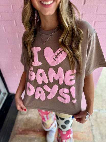 Brown I Heart Game Day Tee with pink "I [heart] GAME DAYS!" and football-stitched heart. Available in sizes S–XXL.