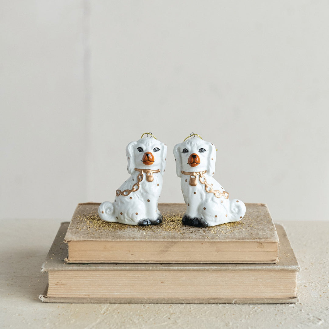 Two white ceramic Staffordshire dog ornaments with gold accents.
