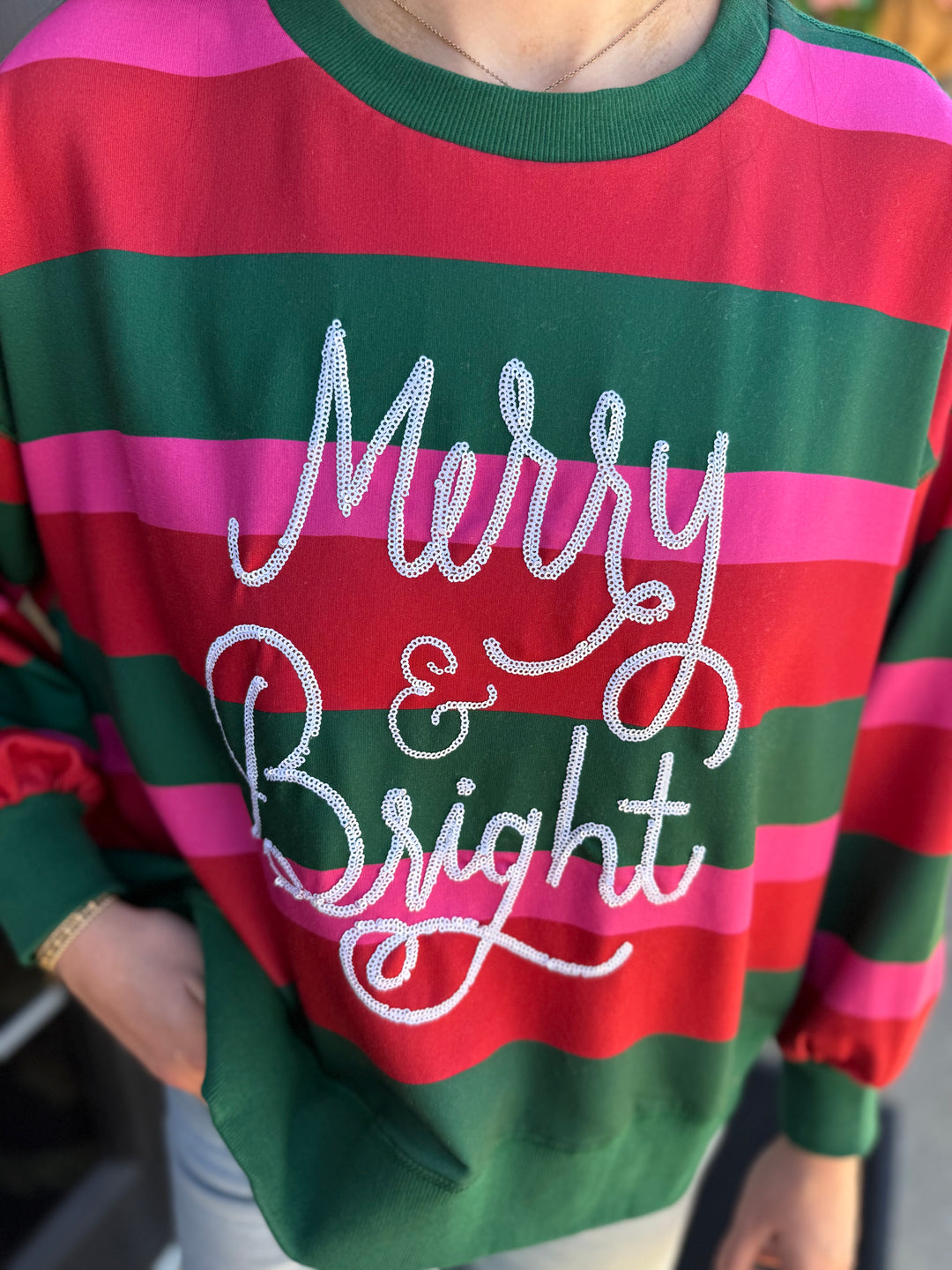 Millie Merry &amp; Bright Sweatshirt in green, red, and pink stripes with “Merry &amp; Bright” in white script sequins. Available in various sizes.