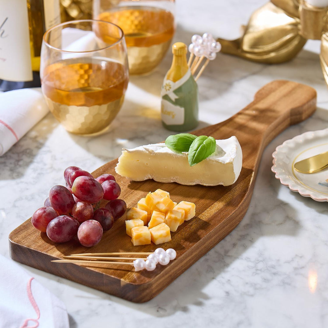 Acacia wood Champagne Toast Charcuterie Board with red grapes, cubed cheese, and a brie wedge garnished with basil. Available in small, medium, and large sizes.