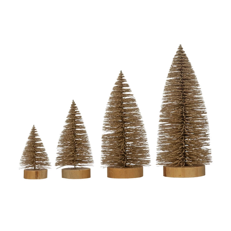 Four champagne-colored glitter bottle brush trees in varying heights on wooden bases.