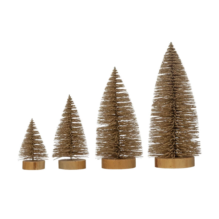 Four champagne-colored glitter bottle brush trees in varying heights on wooden bases.
