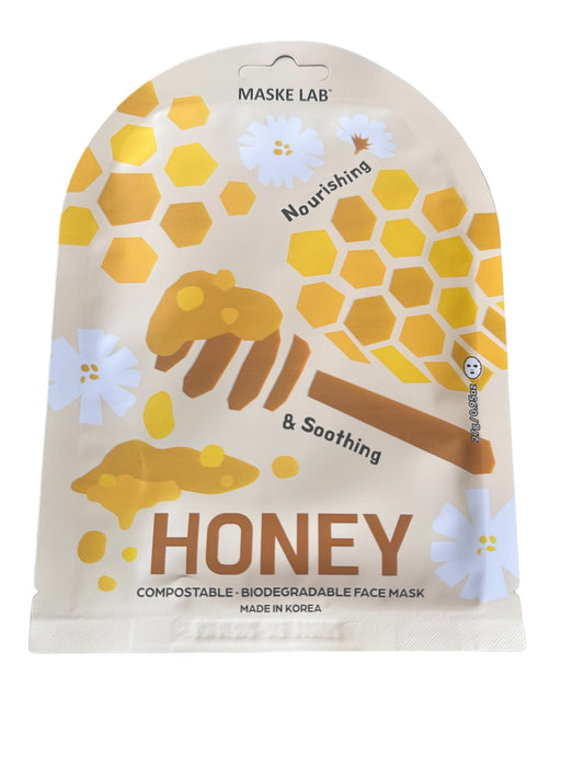 Maske Face Mask packet from Maske Lab. Design: honeycomb, honey dipper with honey, white flowers. Text: "Nourishing & Soothing," "HONEY," "Compostable - Biodegradable Face Mask," and "Made in Korea." Available in single-size packs.