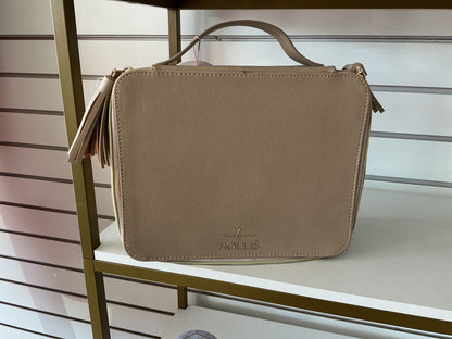 Tan rectangular Hollis Travel Make Up Bag with top handle, tassel zipper, and embossed logo on front; available in small, medium, and large sizes.