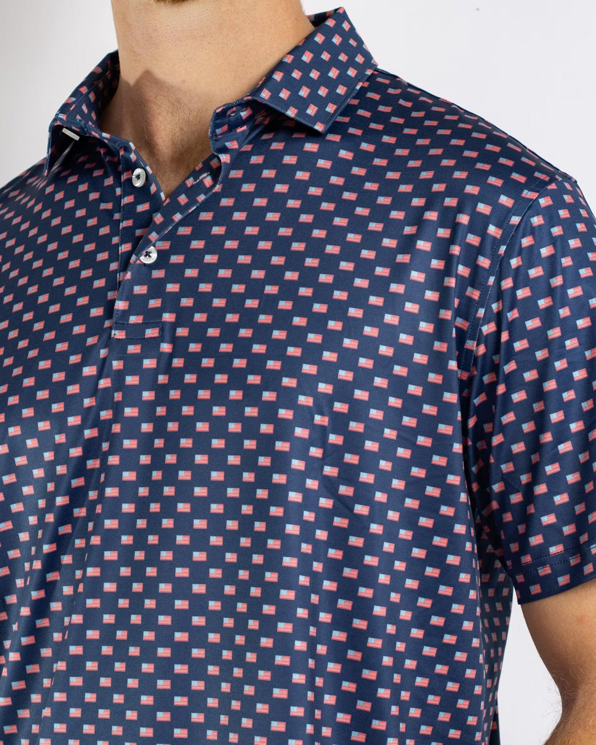 Men’s Americana Performance Polo in navy blue with a repeating red and white rectangle pattern, classic collar, and buttons. Available in sizes S-XXL.