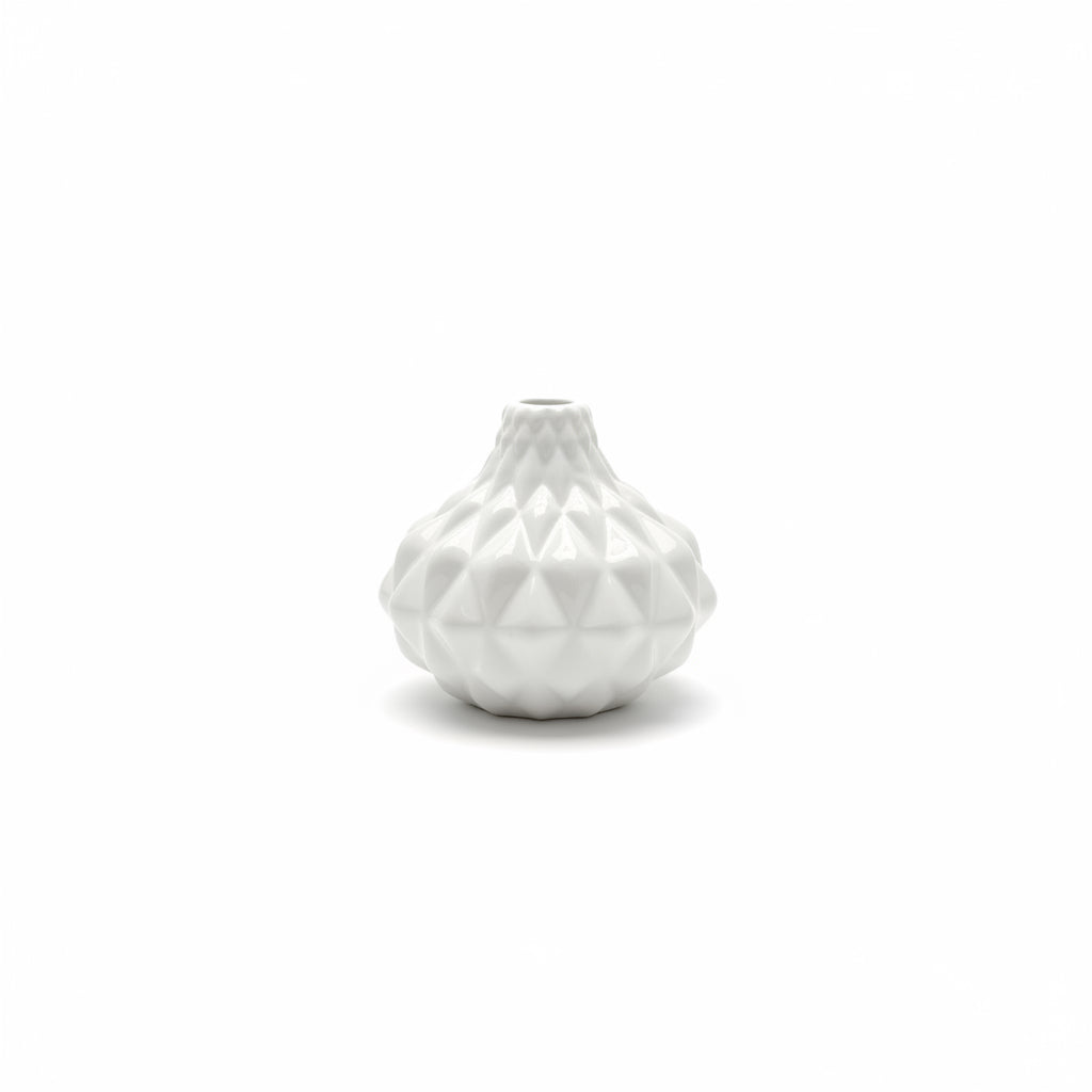 The Artisan Carved Vase is a small white ceramic vase with a geometric, faceted surface design. Sizes available: small.