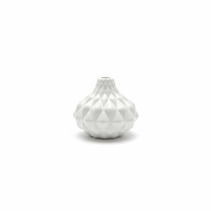 The Artisan Carved Vase is a small white ceramic vase with a geometric, faceted surface design. Sizes available: small.