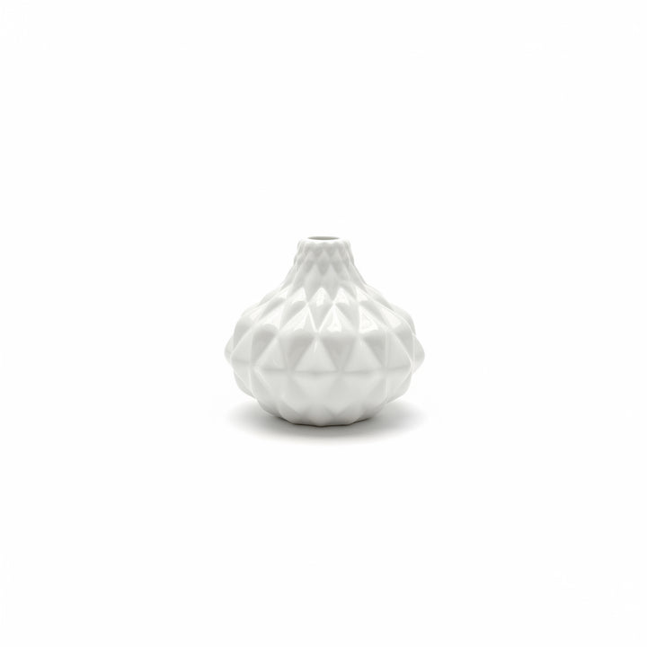 The Artisan Carved Vase is a small white ceramic vase with a geometric, faceted surface design. Sizes available: small.