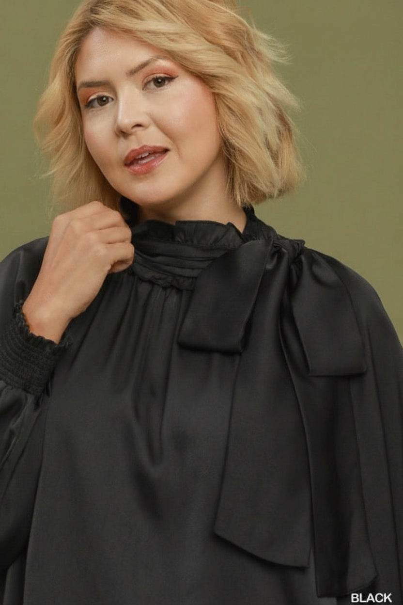 Black satin dress with long sleeves, high neck, and tie bow detail. Available in plus sizes.