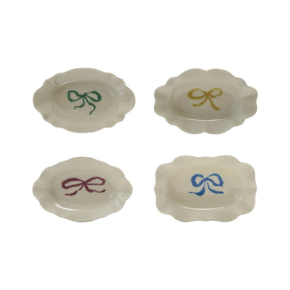 Four white stoneware scalloped dishes with green, yellow, purple, and blue bows. Available in small and medium sizes.