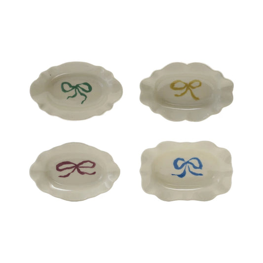 Four white stoneware scalloped dishes with green, yellow, purple, and blue bows. Available in small and medium sizes.