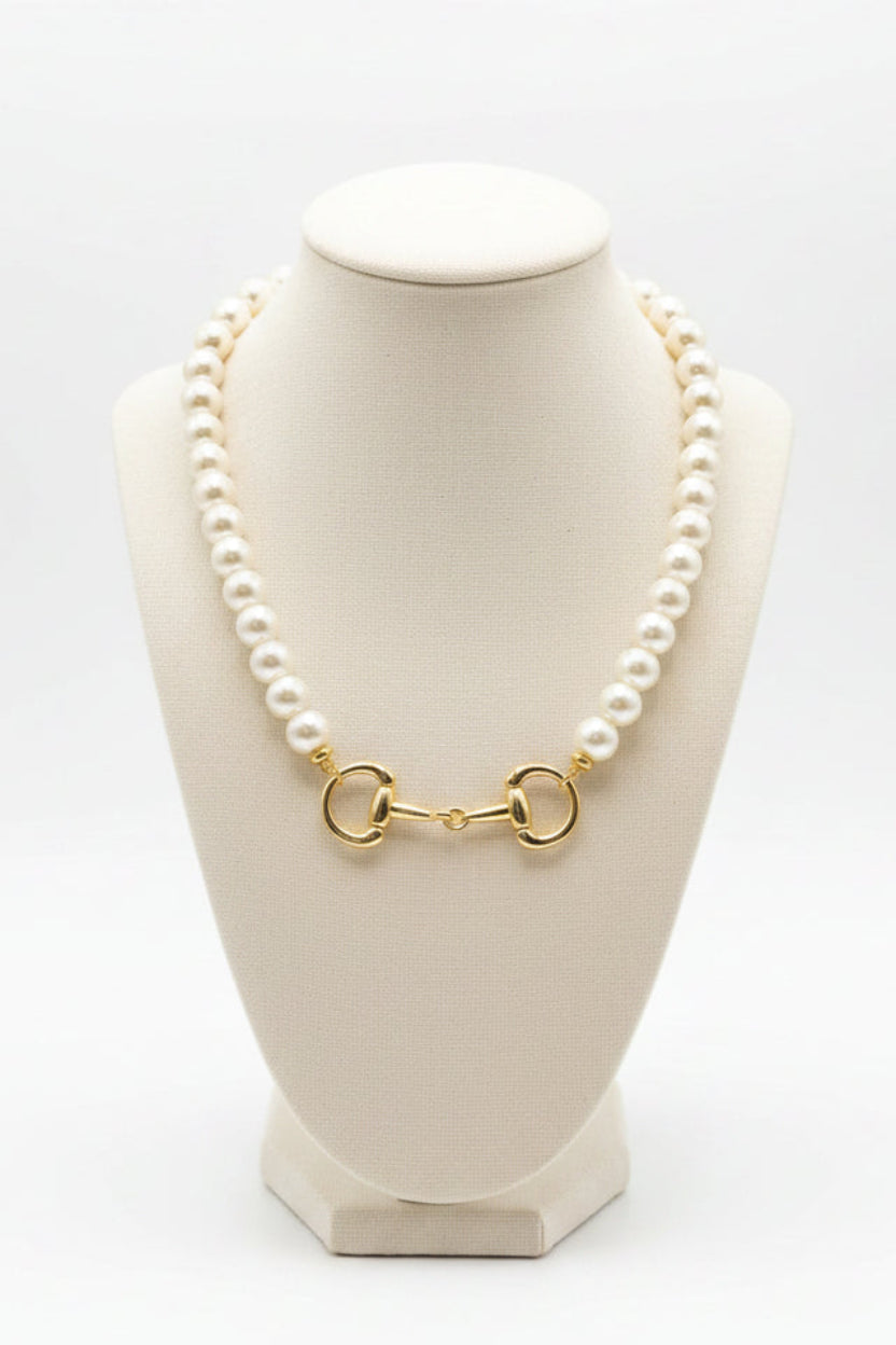 The Betty Pearl Necklace showcases large white pearls with a gold horse-bit detail clasp; available in 16, 18, and 20 inch lengths.