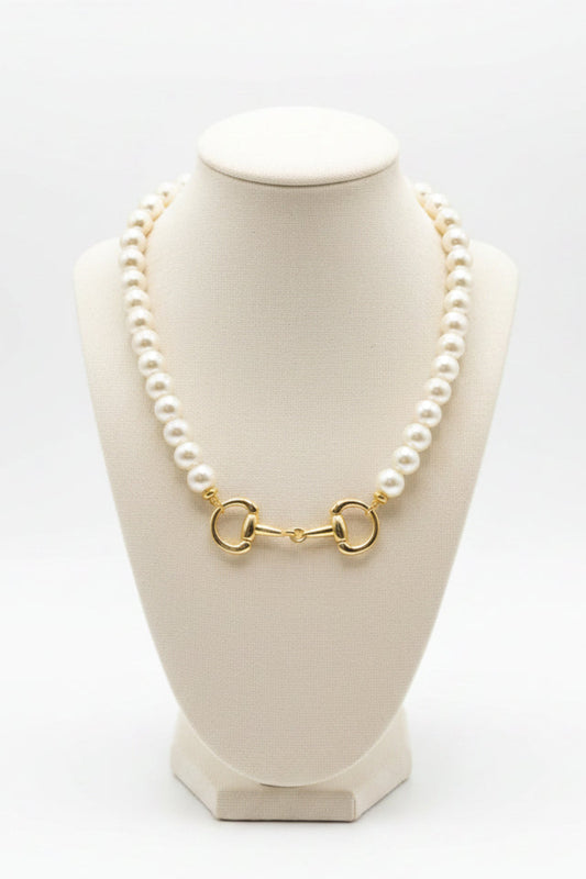 The Betty Pearl Necklace showcases large white pearls with a gold horse-bit detail clasp; available in 16, 18, and 20 inch lengths.