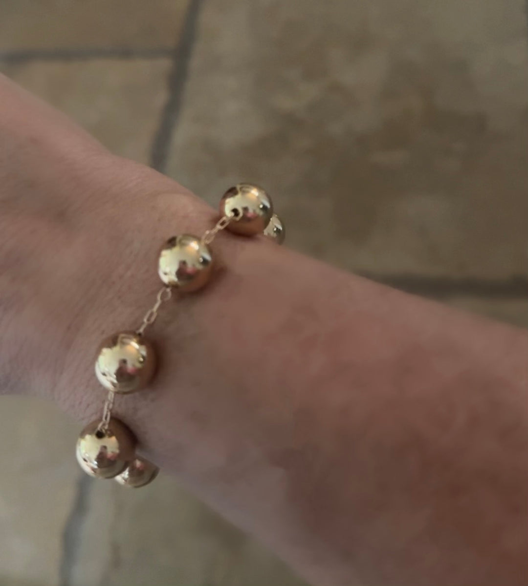 The Beaded 10mm Water Resistant Bracelet features large gold beads on a delicate chain with magnetic clasp. Sizes: 6", 7", 8".