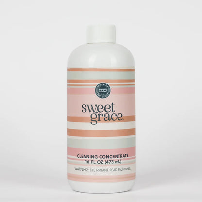 Sweet Grace Cleaning Concentrate, 16 fl oz (473 mL), with pink and beige stripes and a label warning: “Eye irritant. Read back panel.”.