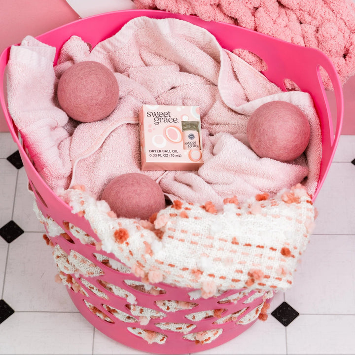 Three wool dryer balls and a bottle of Sweet Grace Dryer Ball Refill.